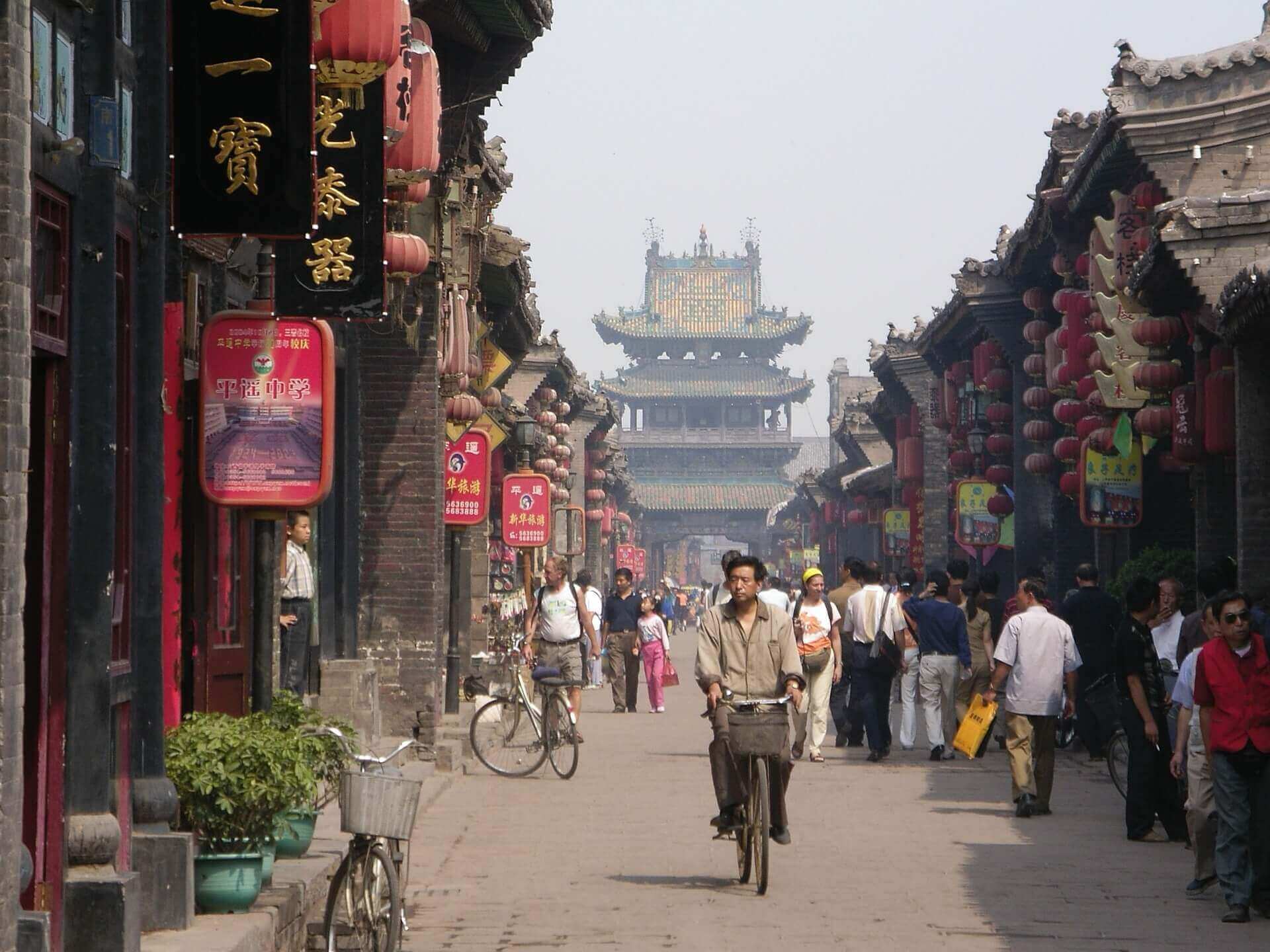 China- Bustling historic street scene with locals, lanterns and bicycles in a traditional Chinese town. 