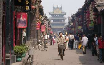 China- Bustling historic street scene with locals, lanterns and bicycles in a traditional Chinese town. 