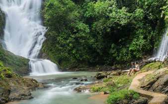 A couple enjoys the view at Los Campesinos Waterfall, where tiers of water cascade through lush Costa Rican rainforest. 
