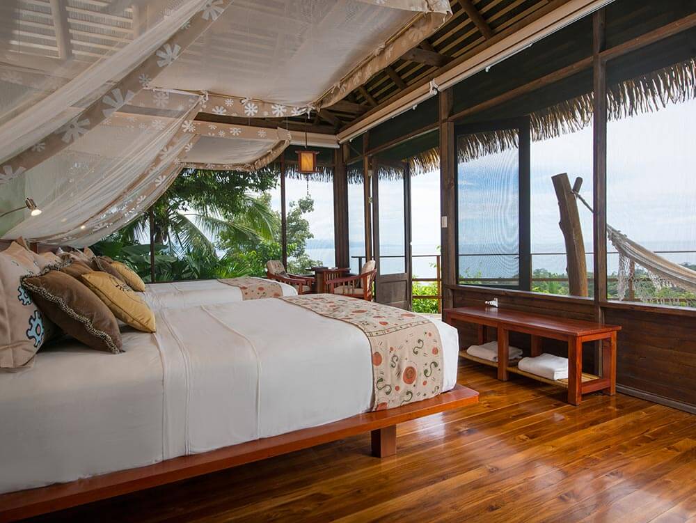 A stylish oceanview suite at Playa Cativo Lodge, featuring canopy bed, hardwood floors, and tropical charm. 