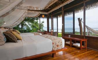 A stylish oceanview suite at Playa Cativo Lodge, featuring canopy bed, hardwood floors, and tropical charm. 