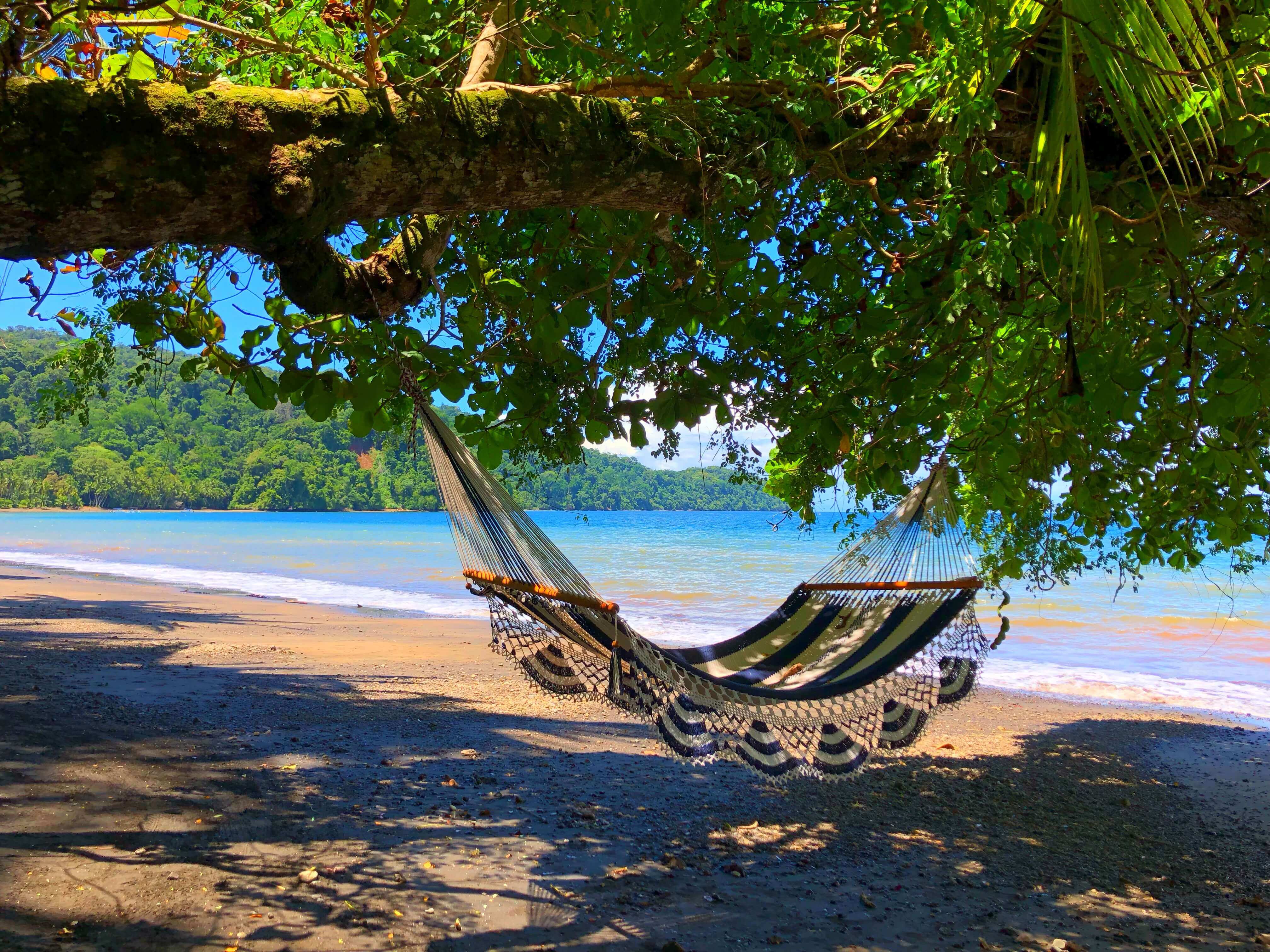A hammock sways in the shade, overlooking the tranquil beach and turquoise waters of Playa Cativo. 