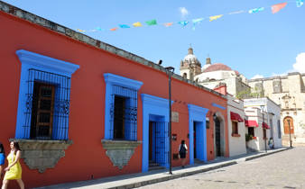 Colourful colonial buildings with bright blue windows and festive papel picado banners in the streets of Oaxaca, Mexico. 