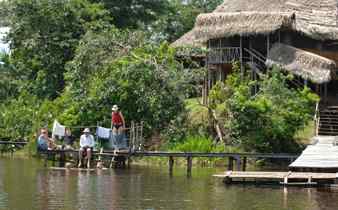 Guests relaxing by the water at an Amazon jungle lodge surrounded by rainforest, Brazil. 