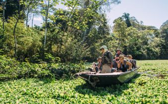 Tourists on a guided boat tour exploring the Amazon jungle and wildlife in Peru. 
