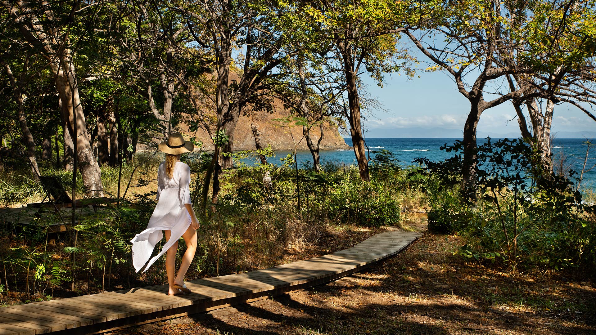 Woman walking along a forest path towards the ocean at Kasiiya, Costa Rica. 