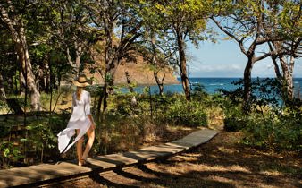 Woman walking along a forest path towards the ocean at Kasiiya, Costa Rica. 