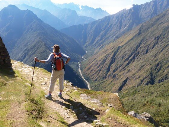 A hiker stands triumphantly atop the Andes, overlooking the Sacred Valley's endless ridges. 