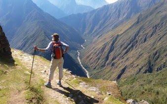 A hiker stands triumphantly atop the Andes, overlooking the Sacred Valley's endless ridges. 