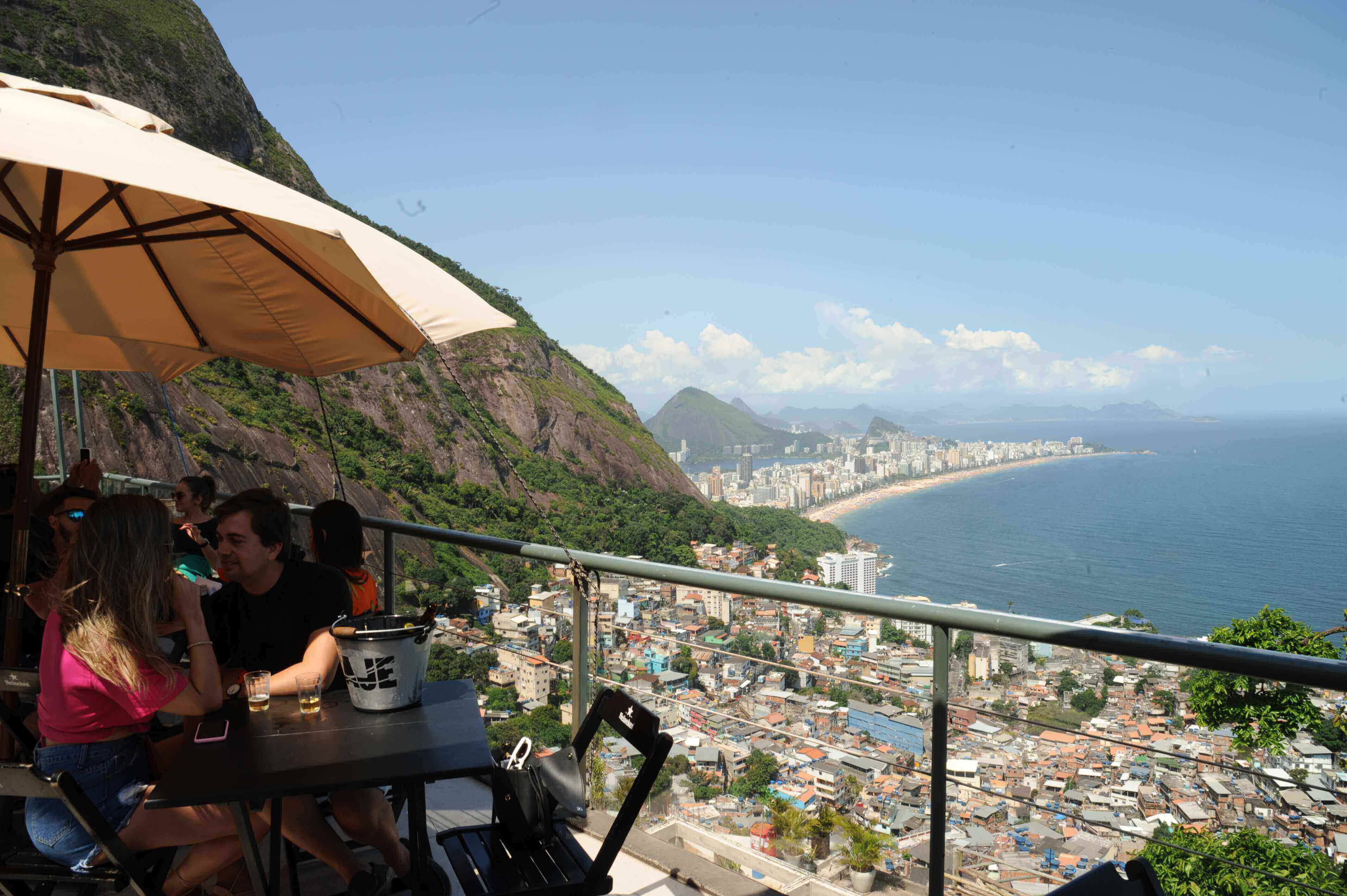 Tourists enjoying drinks with panoramic views over Rio de Janeiro and the favelas from a veranda cafe. 