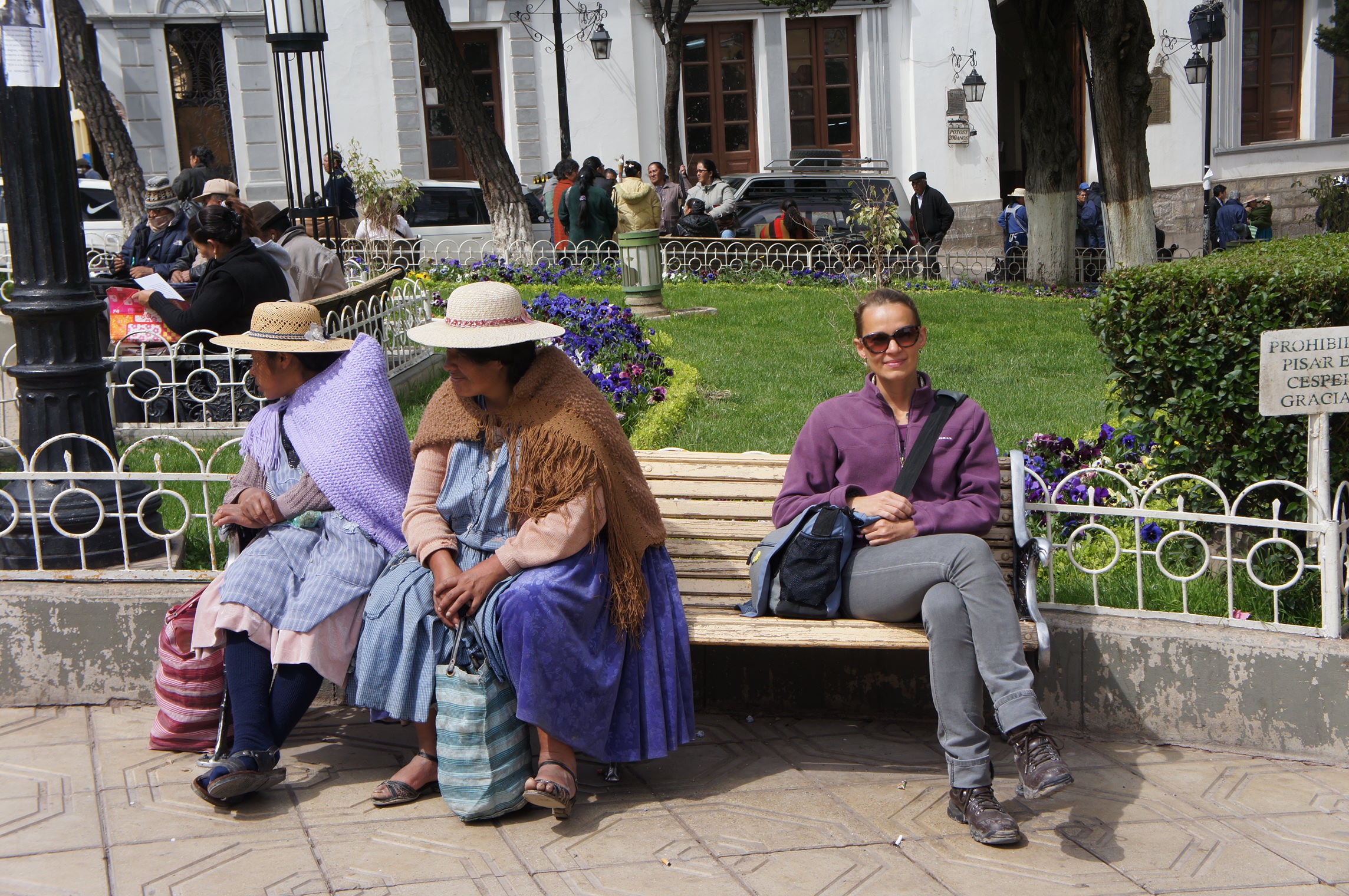 Locals relax on park benches in Bolivia, blending traditional and modern styles. 