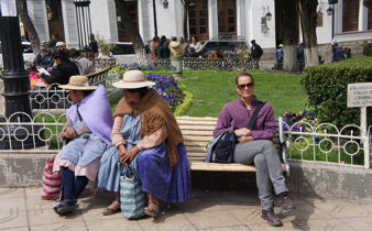 Locals relax on park benches in Bolivia, blending traditional and modern styles. 
