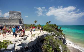 Visitors explore the cliffside Mayan ruins of Tulum overlooking the turquoise Caribbean Sea in Mexico's Yucatan Peninsula. 