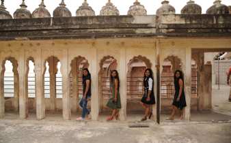 India- Young women exploring heritage architecture with Mughal-style arches in a historic palace. 