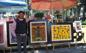 Mexican artists showcasing vibrant handmade paintings at an outdoor market in Mexico City. 
