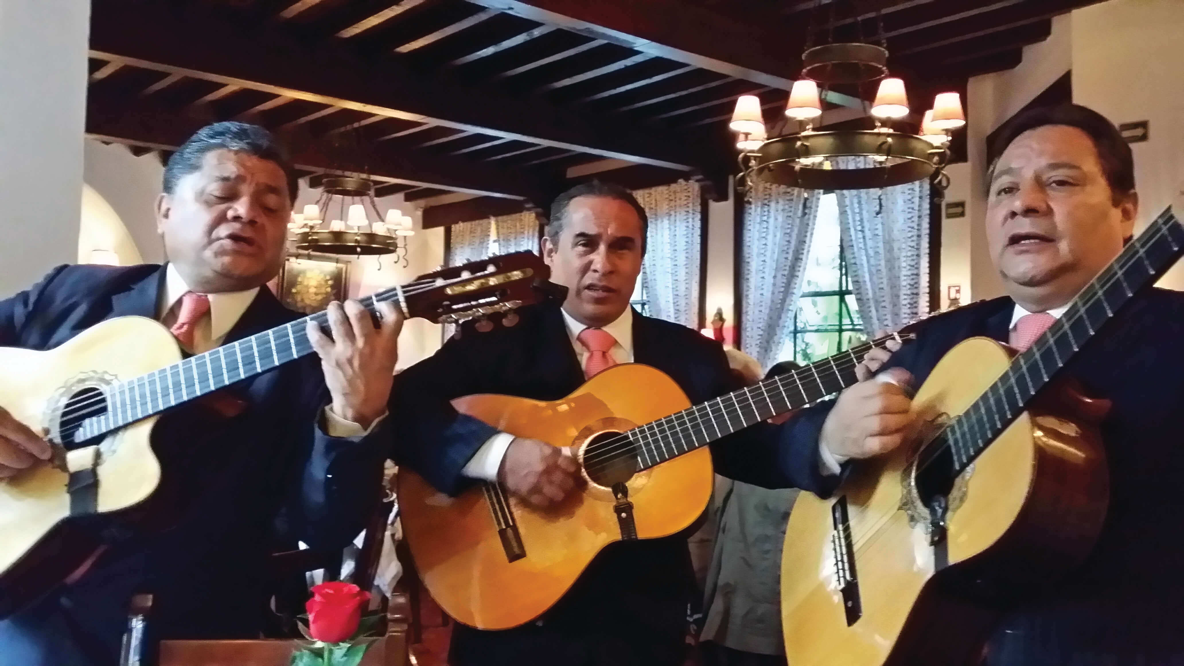 Three traditional Mexican guitarists perform indoors, capturing the spirit and musical heritage of Mexico. 