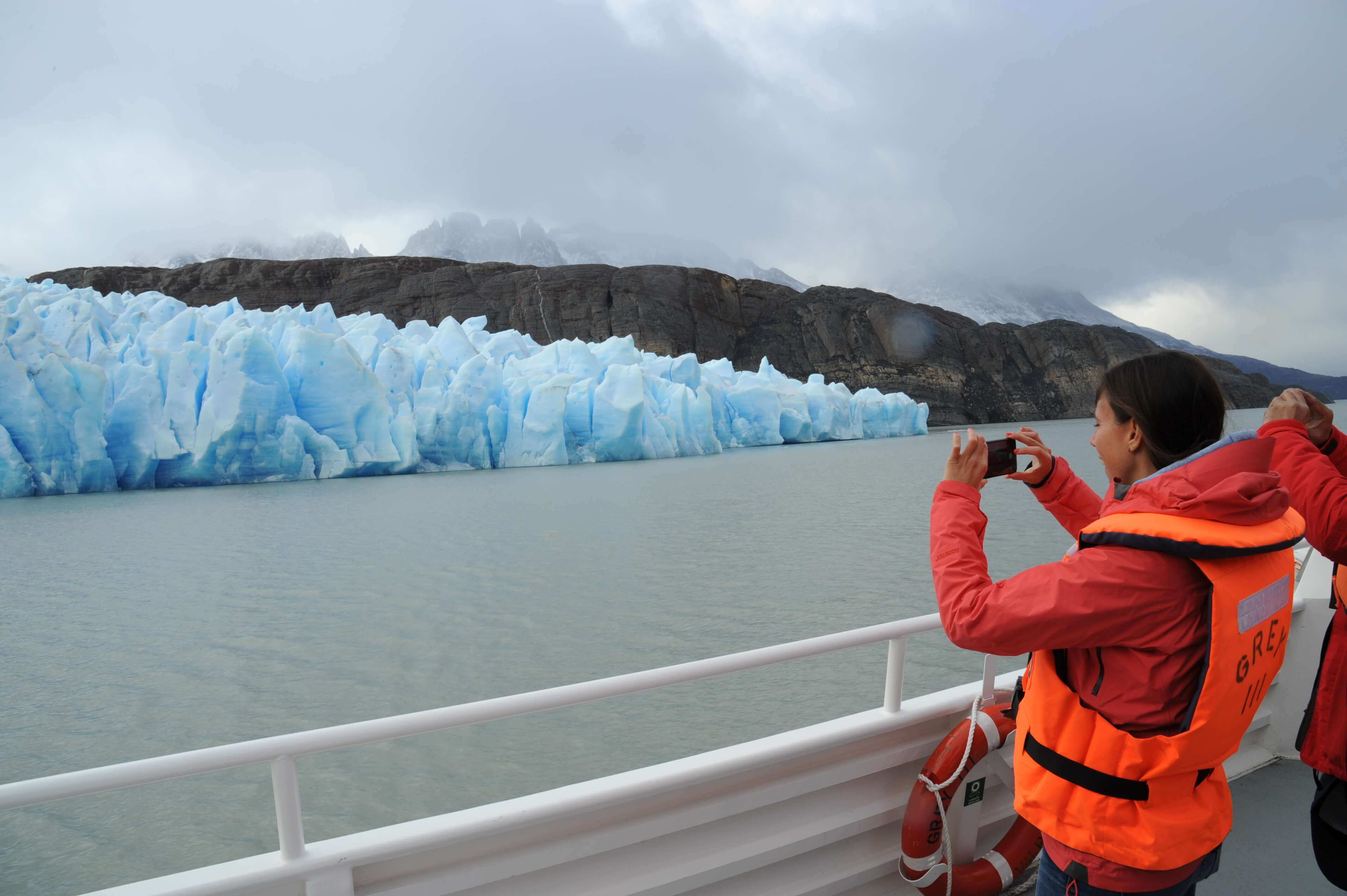 A tourist captures a photo of a brilliant blue glacier from the deck of a boat in Chile's Torres del Paine National Park. 