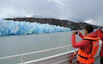 A tourist captures a photo of a brilliant blue glacier from the deck of a boat in Chile's Torres del Paine National Park. 