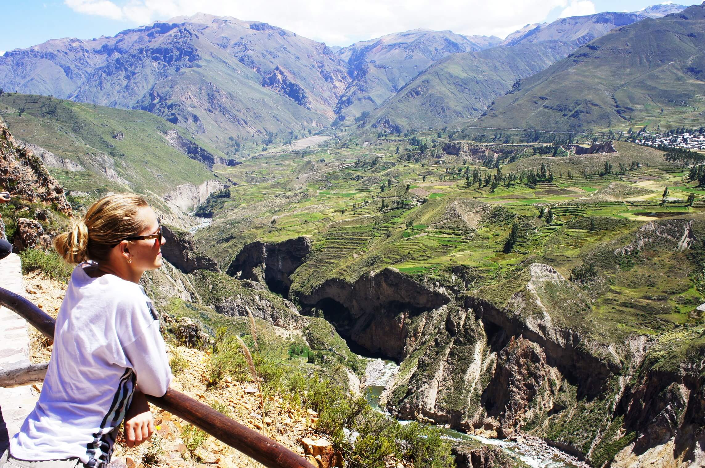 Tourist at Colca Canyon viewpoint overlooking dramatic Andean mountain scenery in Peru. 