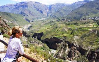 Tourist at Colca Canyon viewpoint overlooking dramatic Andean mountain scenery in Peru. 
