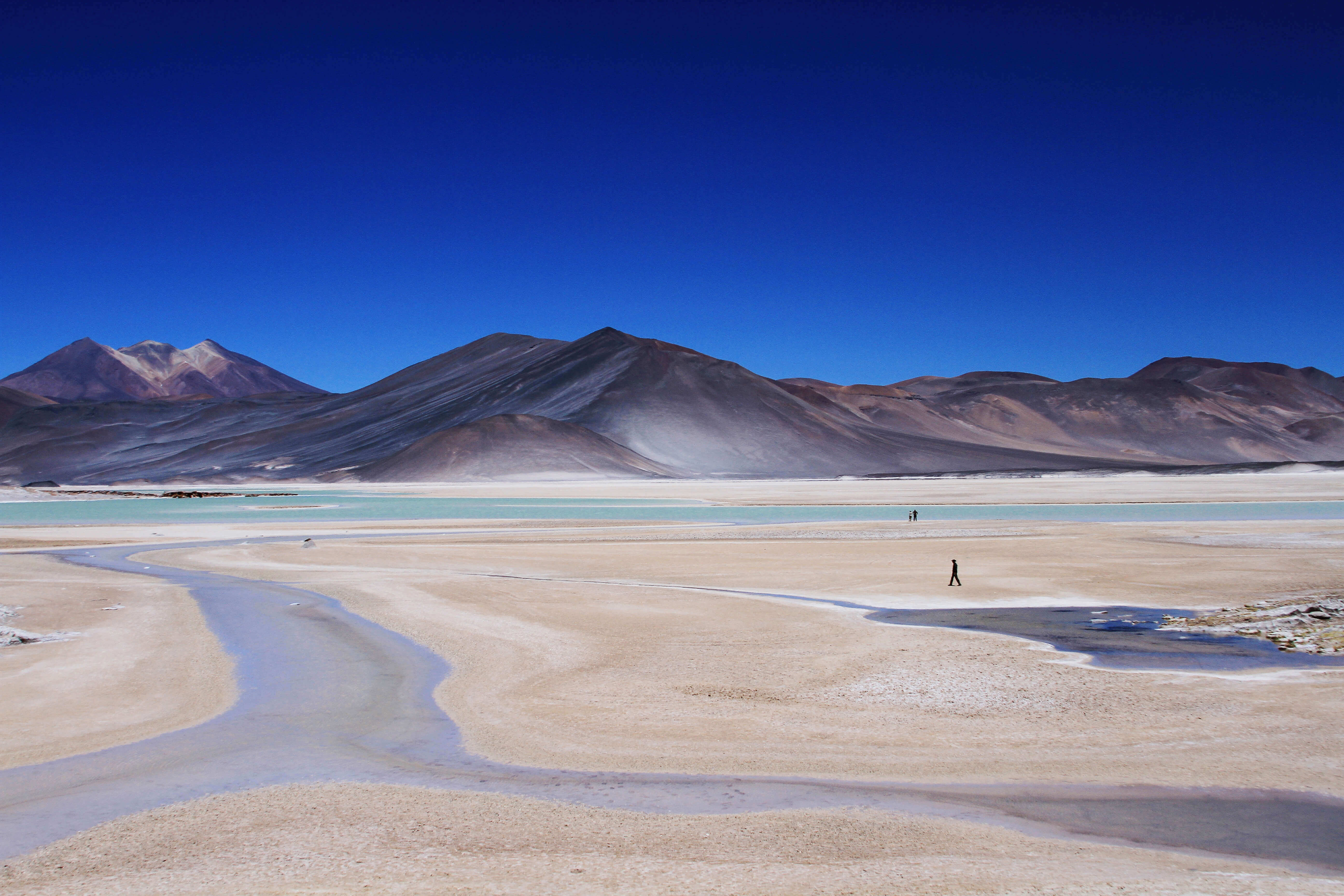 South America - Chile, remote Atacama Desert landscape with salt flats and mountains under blue skies. 