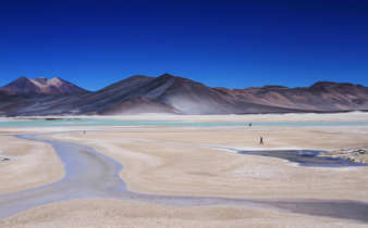 South America - Chile, remote Atacama Desert landscape with salt flats and mountains under blue skies. 
