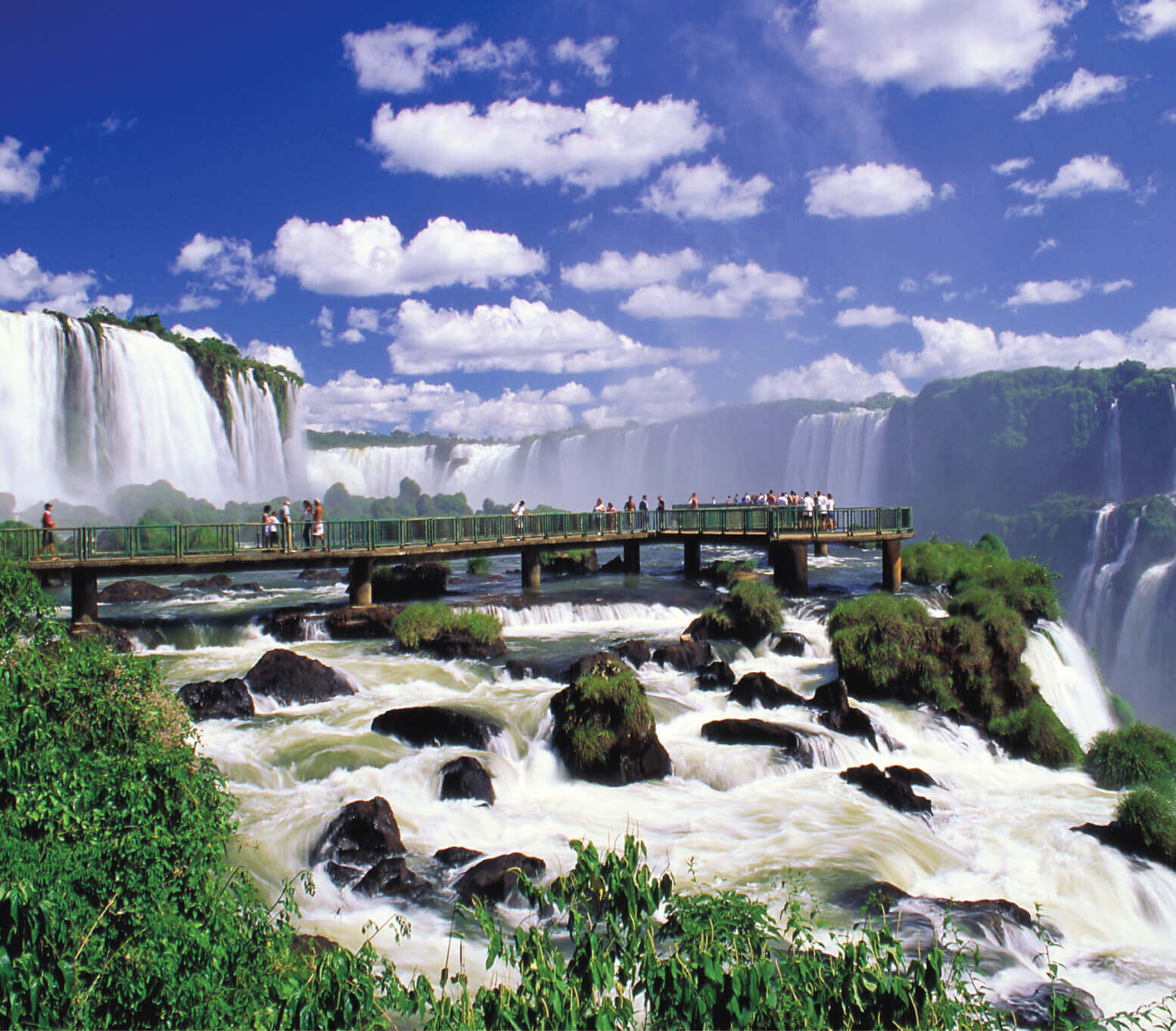 Visitors walk the boardwalk at Iguassu Falls, Brazil, surrounded by thunderous waterfalls. 