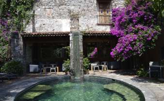 Stone courtyard with small pool, flowering plants, and rustic seating at a boutique hotel in San Miguel de Allende, Mexico. 