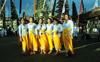 Balinese women in white kebaya and golden sarongs pose during the Galungan festival in Bali, Indonesia. 